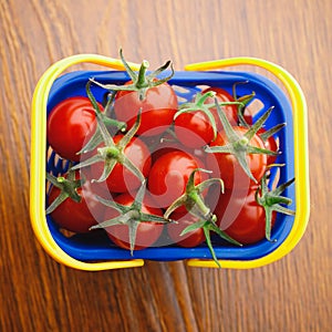 Cherry tomatoes in a shopping basket, wooden background