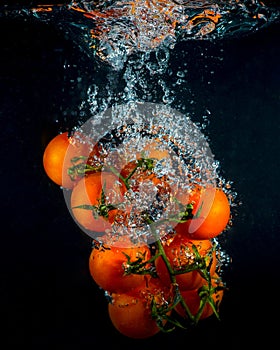 Cherry tomatoes in water splash on black