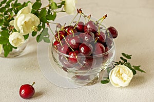 Cherry in a transparent plate. Near a bouquet of roses