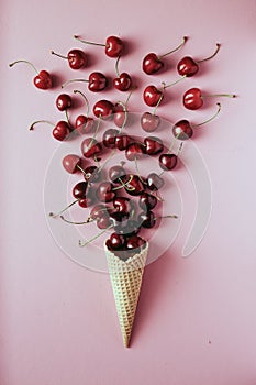 Cherry in waffle cone on pink background, healthy snack, concept flat lay photography and content for food blog