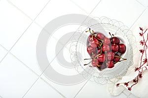 Cherry with water drops on heart shaped plate on white stone table. Fresh ripe cherries. Sweet red cherries. Top view. Rustic styl