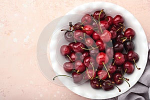 Cherry with water drops on white bowl on pink stone table. Fresh ripe cherries. Sweet red cherries. Top view. Rustic style. Fruit