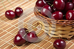 Cherry in a wicker basket on bamboo napkin