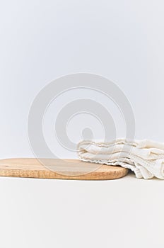 Cherry wood chopping board and white cotton towel on a soft beige table against white wall