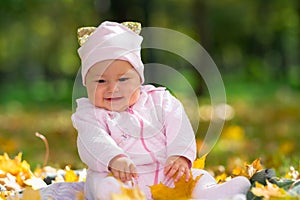 Cherubic baby girl playing with yellow leaves.