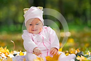 Cherubic baby girl playing with yellow leaves. photo