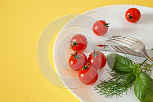 Chery tomatoes on a plate with basil and cutlery