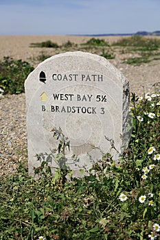 Chesil beach and distance marker on the South West Coast Path, Dorset England