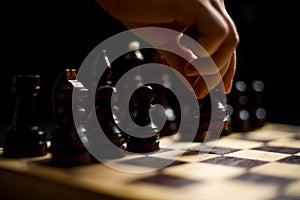 Chess, black`s first move, a man`s hand holding a black pawn