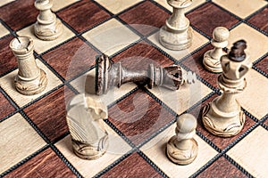 Chess board with black king surrendered to overwhelming force of white chess pieces