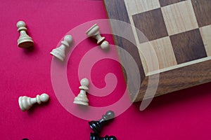 A chess board and black and white pawns over a bright pinkish background