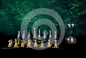 Chess Board and Chess Pieces with Hourglass on a Wooden Table with Mottled Background
