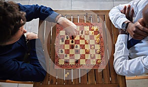 Chess, board game and business men playing at a table from above while moving piece for strategy. Male friends together
