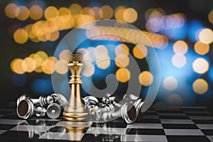 Chess board game with gold king and silver chess pieces on chess board game competition with abstract bokeh night background, mana