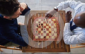 Chess, board game and men playing at a table from above while moving piece for strategy or challenge. Male friends
