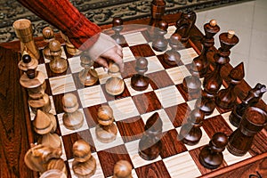 Chess board with large pieces. Game of chess. Man`s hand takes a step by pawn. Set of chess pieces