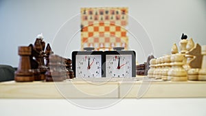 A chess clock is standing next to a chessboard waiting for the start of the game