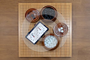 Chess clock timer with black and white go stones in wooden bowls