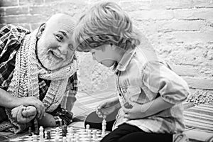 Chess competition. Cute boy developing chess strategy. Grandfather and grandson playing chess. Grandfather and grandson