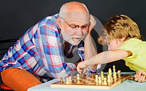 Chess competition. Grandpa and grandson playing chess spending free time together. Brain development and logic concept.