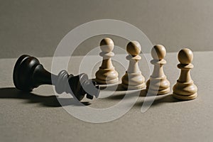 Chess concept of fallen king and standing pawns symbolizing defeat and strategy