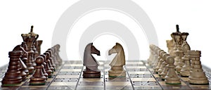 Chess faceoff of both wooden knights on top of a chess board in front of a white background