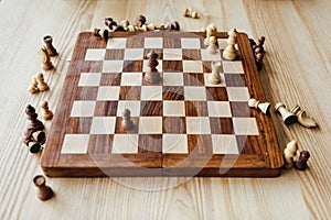 Chess figures scattered on chessboard at the table