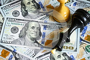 Chess figures on US dollar bills pile, king lies on cash