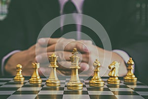 Chess game on chess board behind business man background. Business concept to present financial information and marketing strategy