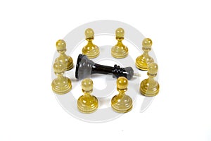 Chess game. The chess piece of the black king lies surrounded by white pawns - isolated on a white background.