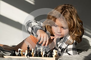 Chess game with kids at home. Chess for intelligent kid. Child genius, smart pupil playing logic board game. Clever