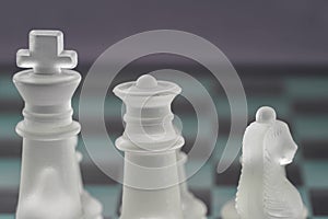 Chess with game pieces made of glass, queen, king, pawn and game board made of glass