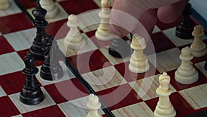 Chess game. Stretegy concept. Close up of businessman hand moving white queen piece on chess board isolated over black