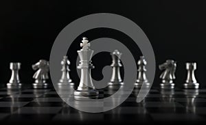 Chess King in front of chess figures in row on black background. Leader, leadership, business strategy, success, victory, win,