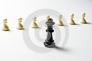 Chess king is standing against white pawns. Symbol of leadership and confrontation. Horizontal frame