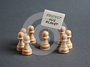 Chess pawn protester holding a sign banner with the message PROTECT OUR PLANET