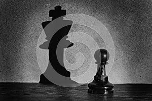 Chess pawn standing in a spotlight that make a shadow actistic photo