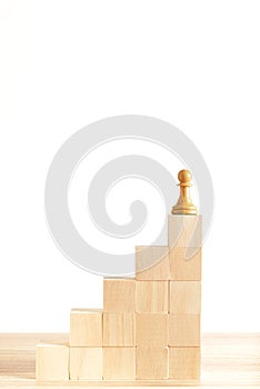 Chess pawn at the top of a stair made of wooden blocks