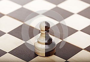 Chess pawn in white and black color standing alone on the chessboard