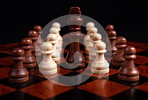 Chess pawns and king on a board on a black background