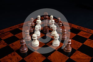Chess pawns and king on a board on a black background