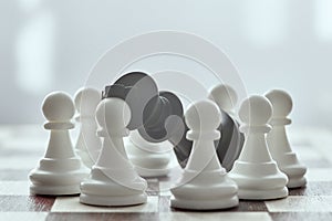 Chess photographed on a chessboard. White pawns surrounded the defeated black king. Gray background in blur