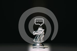 A chess piece of a horse with a message icon above it. Concept of communication and HR.