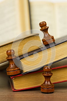 Chess pieces and books on a wooden table.