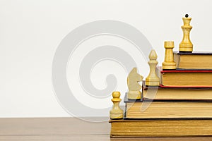 Chess pieces and books on a wooden table.