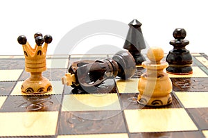 Chess pieces on chess-board with fallen king