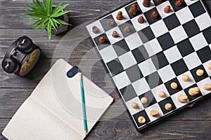 Chess pieces with game board and alarm clock on wooden table