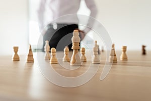 Chess pieces with king in the leading position placed on office desk