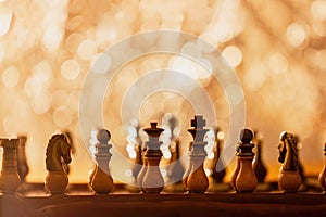 Chess pieces placed on chess board, beginning of game. Abstract shining background with bokeh