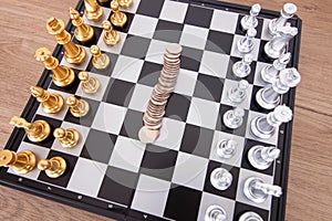 Chess pieces placed on the chessboard and the dollar coin in the middle